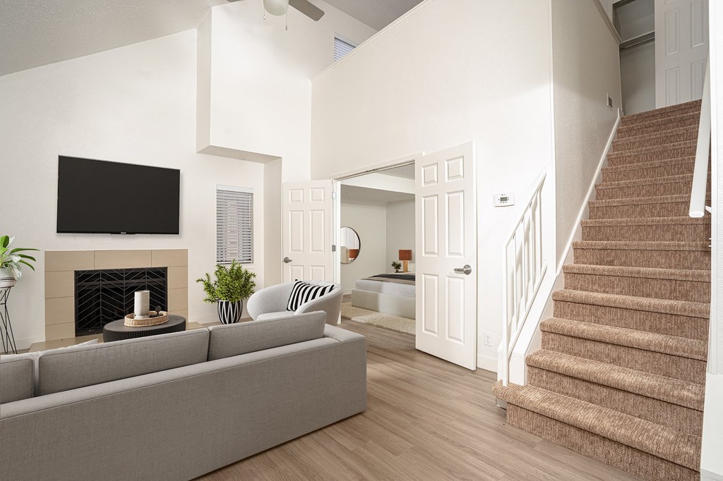 a living room with a staircase and a tv above a fireplace